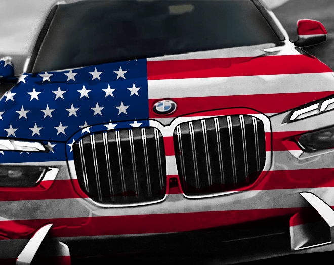 BMW vyrobené v EU, pokryté americkou vlajkou, na silnici symbolizující nižší ceny v USA oproti ČR.