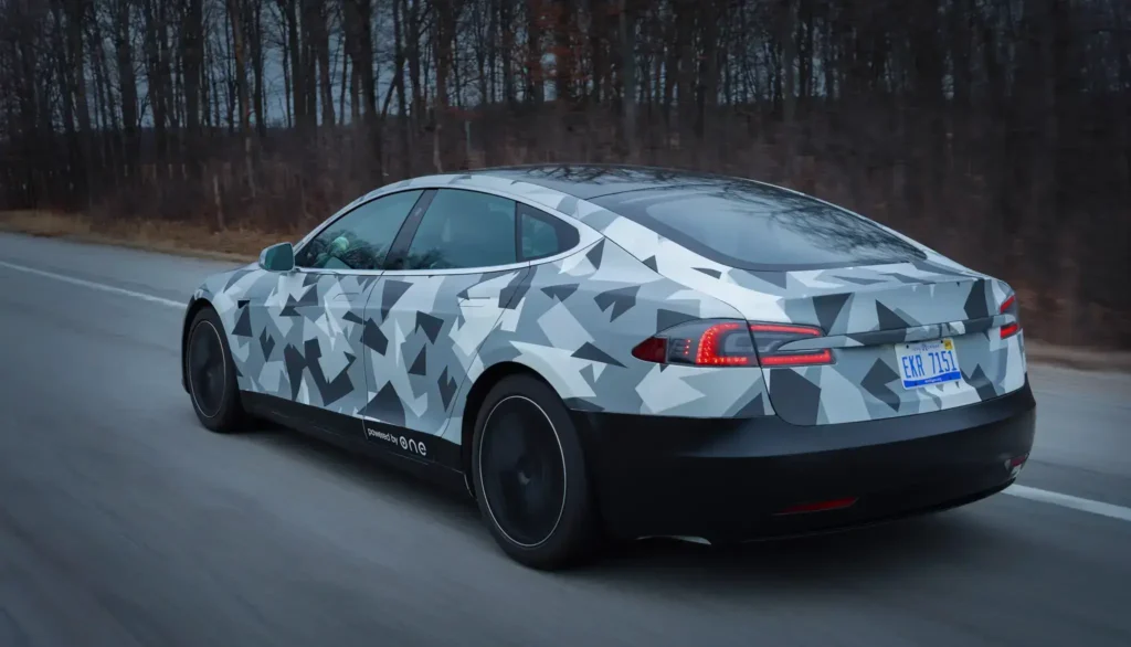 Elektromobil Tesla Model S vybavený baterií od společnosti ONE, která výrazně navyšuje jeho dojezd. Fotografie zachycuje vůz na silnici během jízdy, ukazující moderní design a vylepšenou výkonnost díky nové baterii.