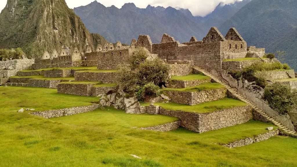 Zelené terasy a kamenné stavby Machu Picchu, s majestátními horami v pozadí, ilustrující pokročilé zemědělské a stavební techniky Inků.