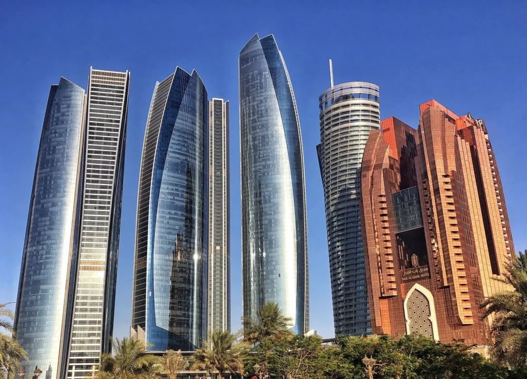 Blízký pohled na ikonické mrakodrapy Etihad Towers v Abu Dhabi, které se tyčí proti jasné modré obloze, představující moderní architekturu a luxus města.