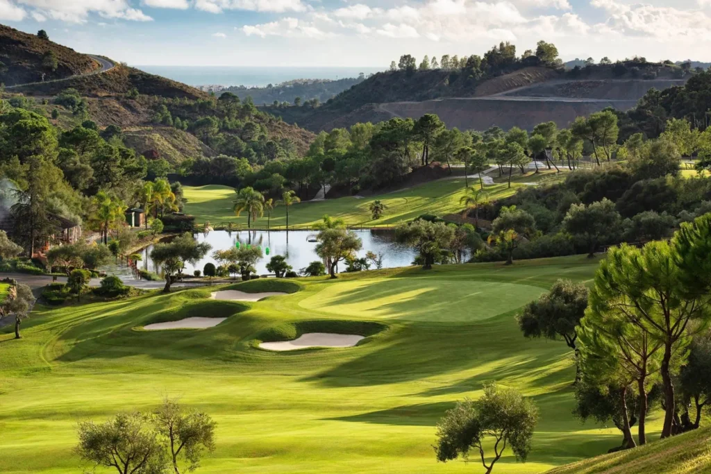 Golfové hřiště v Marbella Golf Club Resort ve Španělsku, obklopené bujnou zelení, jezírky a malebnými kopci. Ideální destinace pro milovníky golfu s úchvatnými výhledy a perfektně udržovanými fairwayi.