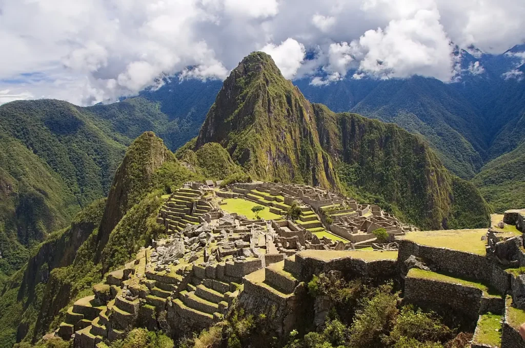 Panoramatický pohled na Machu Picchu, starověké incké město v Peru, obklopené bujnými zelenými horami a tajemnými oblaky.