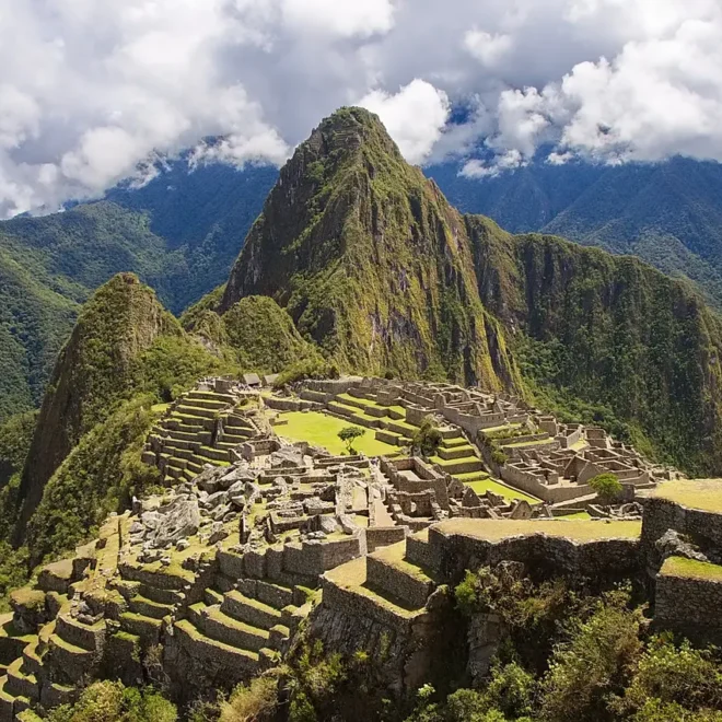 Panoramatický pohled na Machu Picchu, starověké incké město v Peru, obklopené bujnými zelenými horami a tajemnými oblaky.