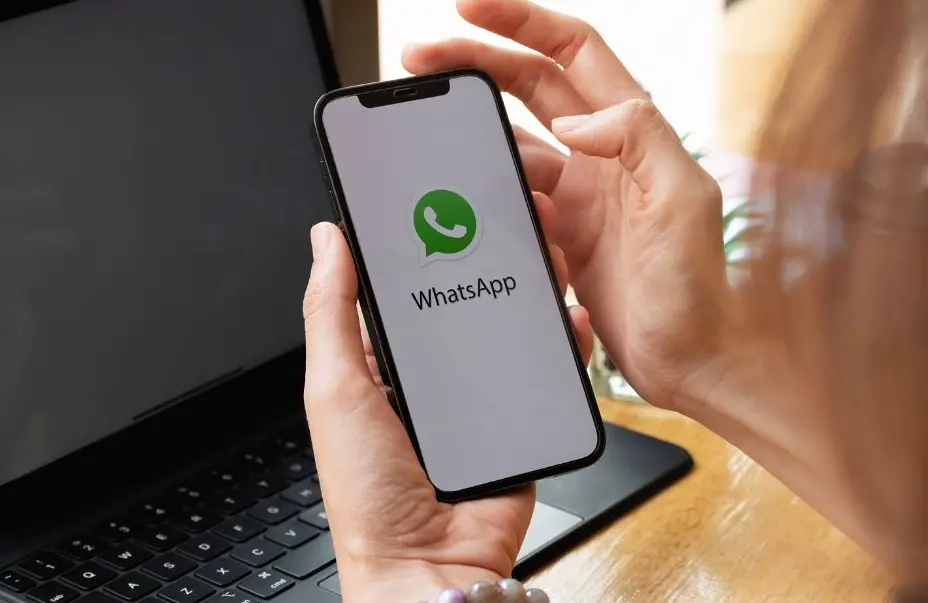 Používání aplikace WhatsApp na mobilním telefonu s notebookem v pozadí.