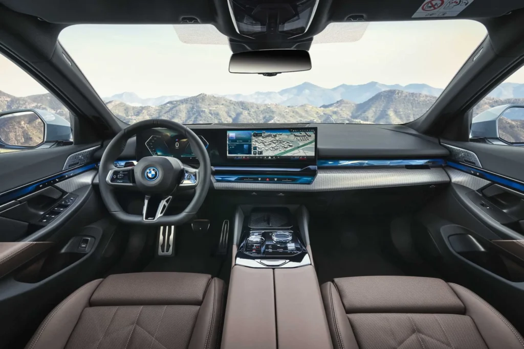 Moderní interiér BMW i5 eDrive40 s pokročilým infotainment systémem a panoramatickým výhledem na hory.