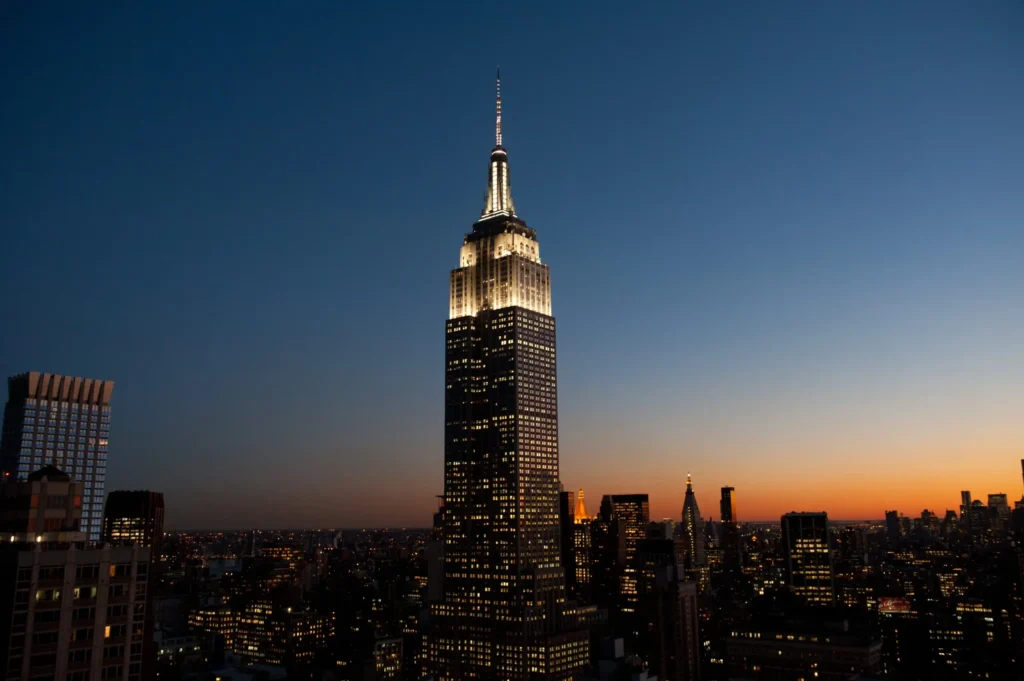 Empire State Building v New Yorku osvětlený za soumraku s městským panoramatem v pozadí