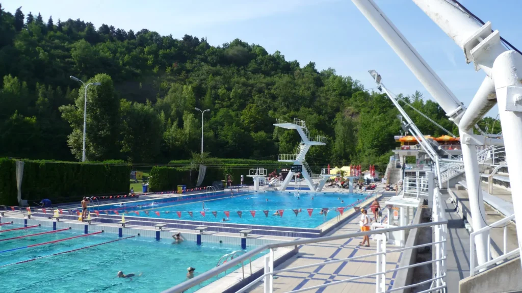 Koupaliště v Praze obklopené zelení, s plaveckým bazénem a skokanskou věží