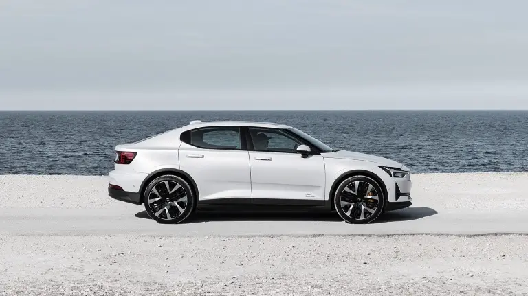 Bílý Polestar 2 Long Range Dual Motor zaparkovaný na pobřeží s výhledem na moře, představující čistý skandinávský design a špičkovou technologii elektromobilu.