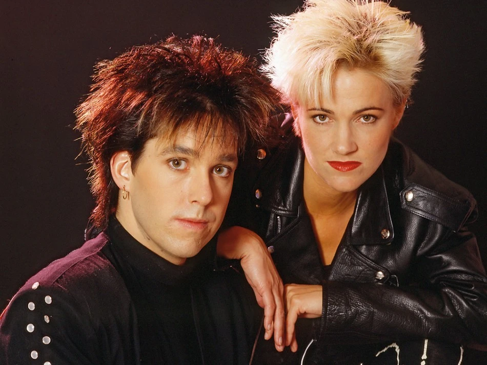 Per Gessle a Marie Fredriksson z Roxette v černých kožených bundách během 80. let, pózující s výraznými účesy typickými pro tehdejší dobu.