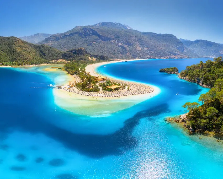 Modrá laguna v Ölüdeniz, Turecko, nabízí dechberoucí výhledy na tyrkysově modré vody obklopené zelenými kopci. Tato oblíbená turistická destinace je známá svými plážemi s jemným pískem a klidným mořem, ideální pro relaxaci a vodní sporty.