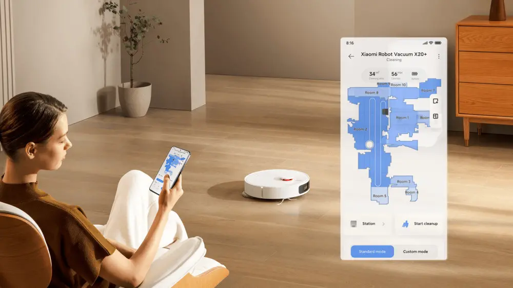 Žena ovládá robotický vysavač Xiaomi Robot Vacuum X20 Plus pomocí mobilní aplikace, která zobrazuje mapu místností a průběh úklidu na jejím chytrém telefonu.