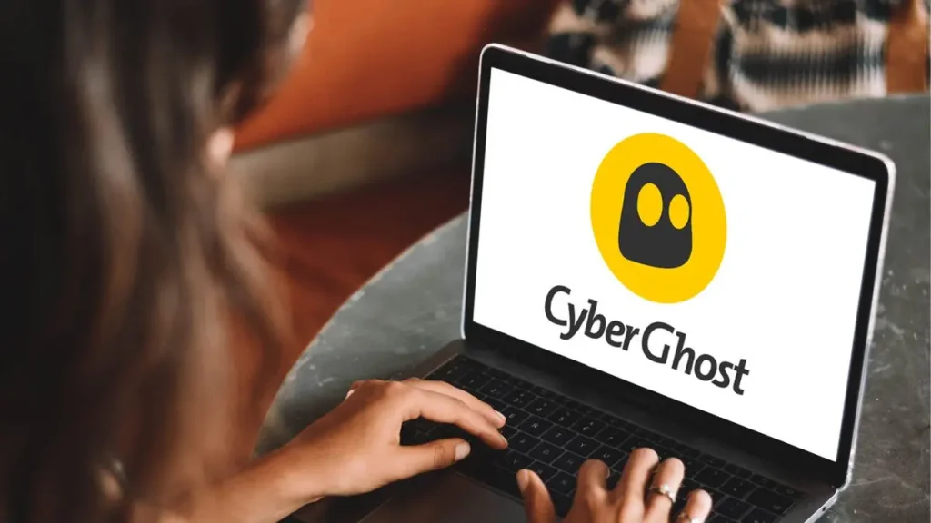 Uživatel pracuje na notebooku s otevřenou aplikací CyberGhost VPN, logo služby je zobrazeno na obrazovce.