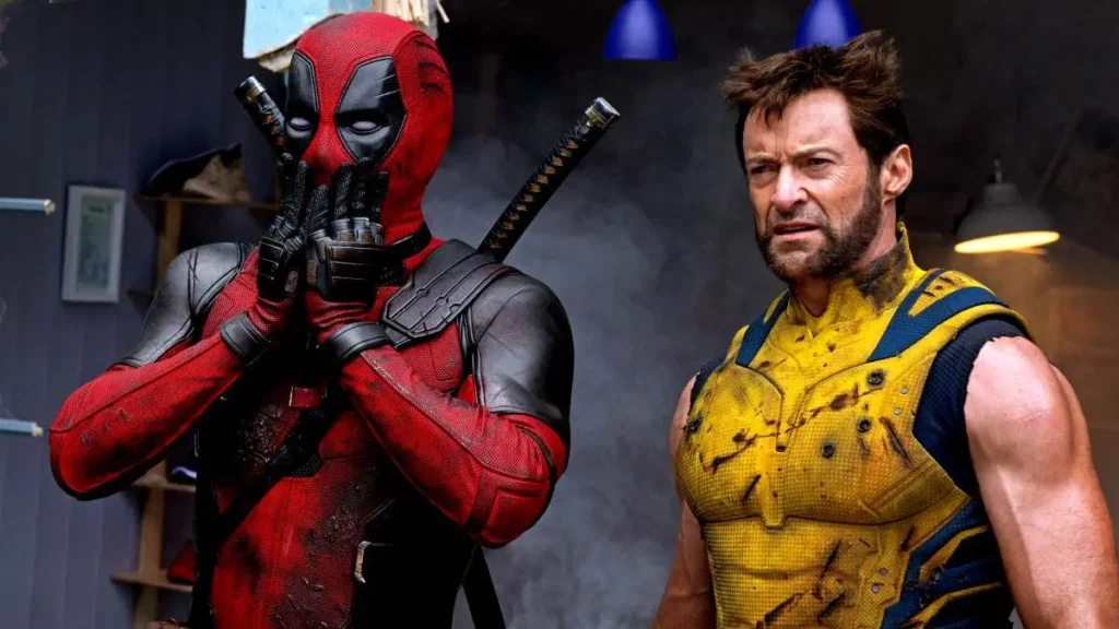 Deadpool a Wolverine stojí vedle sebe, Deadpool je v červeném kostýmu, drží si ruce před obličejem a Wolverine má na sobě žlutý a modrý kostým, tváří se odhodlaně.