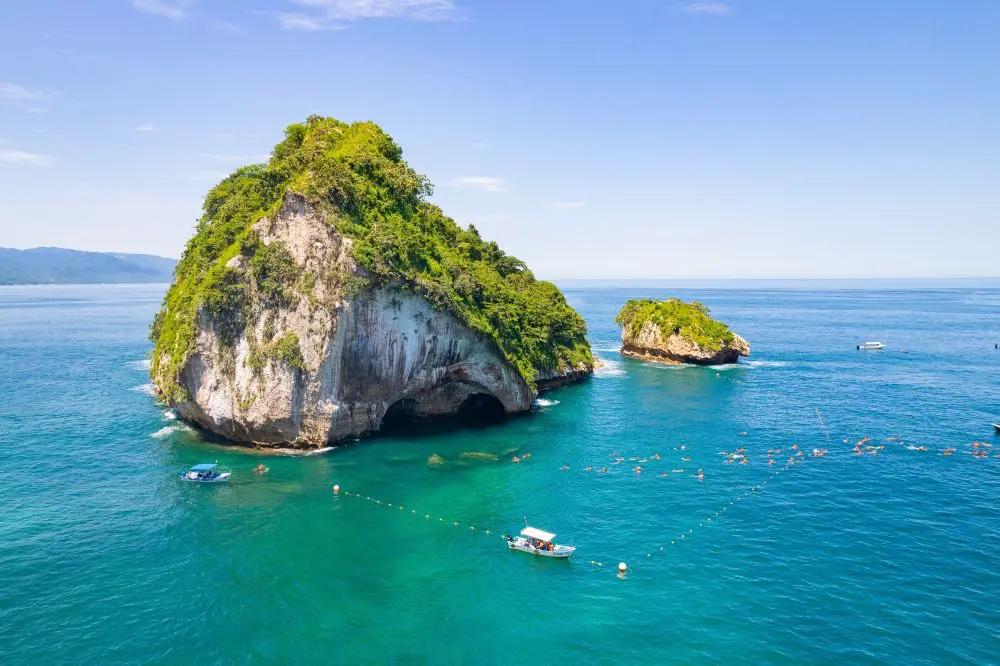 Skalnaté ostrůvky s bujnou zelení v oceánu u pobřeží Puerto Vallarta, Mexiko.