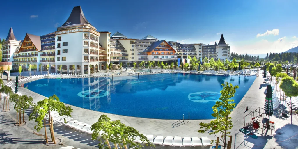 Hotel Gołębiewski w Karpaczu s velkým venkovním bazénem a moderní architekturou obklopený zelení.