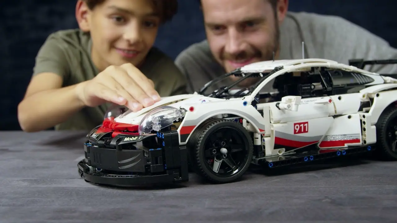 Detailní pohled na LEGO® Technic Porsche 911 RSR, který otec a syn společně sestavili a obdivují jeho realistické prvky.