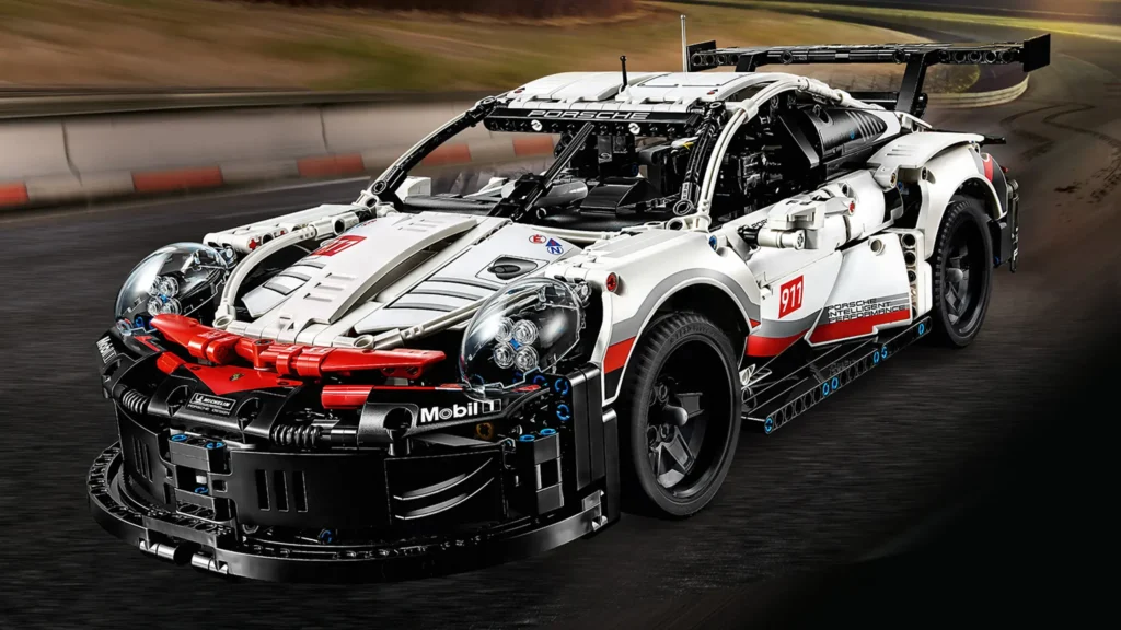 LEGO® Technic model Porsche 911 RSR s realistickými detaily, včetně funkčního diferenciálu, šestiválcového motoru a aerodynamických prvků. Model obsahuje ikonické prvky závodního vozu v bílém, červeném a černém designu.