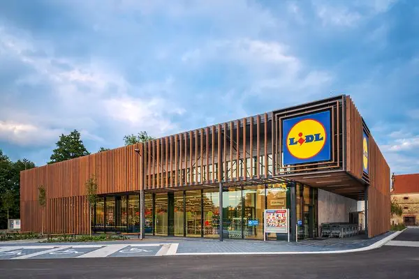 Moderní prodejna Lidl s dřevěným designem fasády a skleněným vchodem.