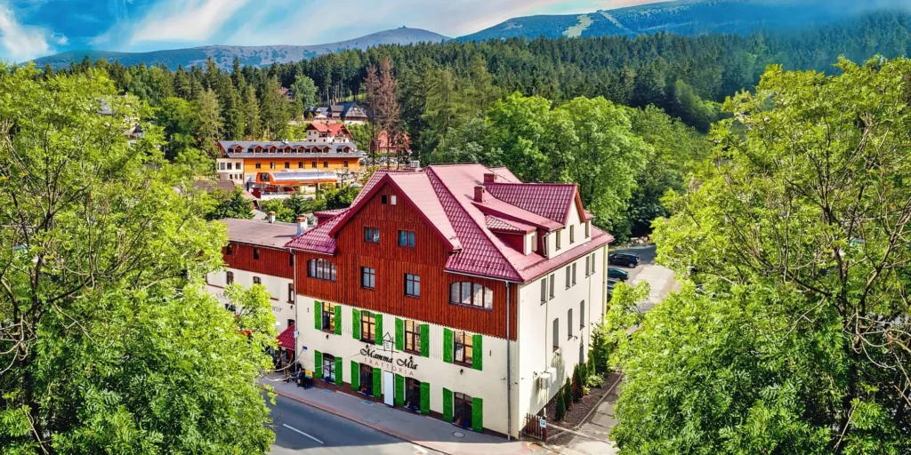 Hotel Leśny Dwór v Karpaczi s rustikálním vzhledem, obklopený hustým lesem, nabízející relaxační pobyt.