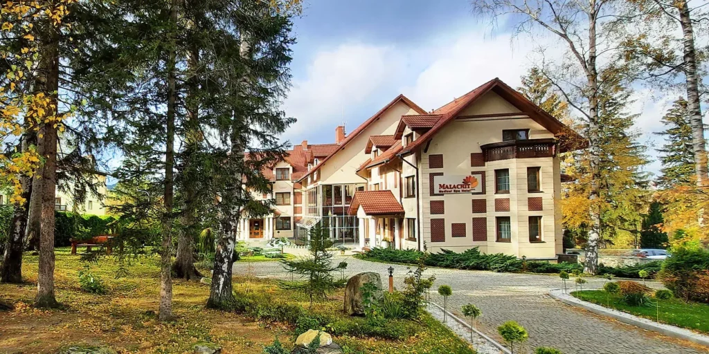 Malachit Karpacz SPA Hotel obklopený stromy a klidnou přírodou, s elegantním exteriérem a příjemnou atmosférou.