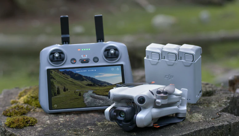 Dron DJI Mini 4 Pro s dálkovým ovladačem a náhradními bateriemi během natáčení na horách.