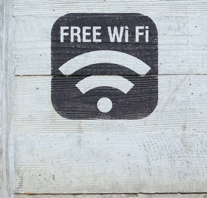 Značka „Free Wi-Fi“ namalovaná na betonové zdi, upozorňující na dostupnost bezplatného připojení k internetu.