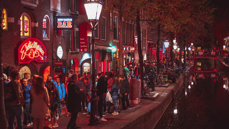 Rušný noční život v Red Light District v Amsterdamu plný turistů a světel.