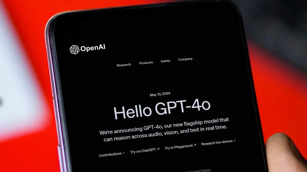 Úvodní stránka OpenAI představující nový model GPT-4o na displeji mobilního telefonu. Text na obrazovce oznamuje spuštění modelu GPT-4o 13. května 2024, který nabízí schopnost analyzovat audio, video a text v reálném čase.