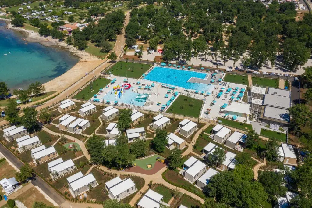 Letecký pohled na Camping Park Umag v Chorvatsku s bazénem, vodními atrakcemi a moderními bungalovy u moře, obklopený zelení a plážemi.