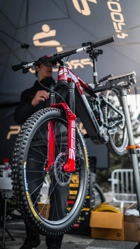 Pohled na elektrokolo CRUSSIS e-RACE PRO připravené k údržbě, s důrazem na přední vidlici RockShox a výkonný motor Bosch.