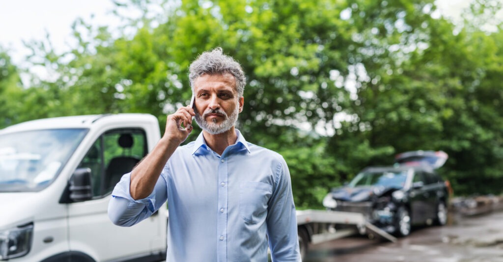 Muž volá asistenční službu po autonehodě, odtahové vozidlo je připraveno na místě nehody. Direct pojišťovna nabízí rychlou pomoc a asistenci při poruchách nebo nehodách po celé Evropě.