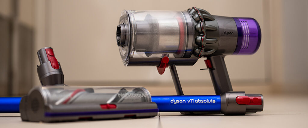 obrázek ukazuje bezdrátový tyčový vysavač Dyson V11 Absolute v detailu s hlavními částmi vysavače, připravený na úklid na podlaze.