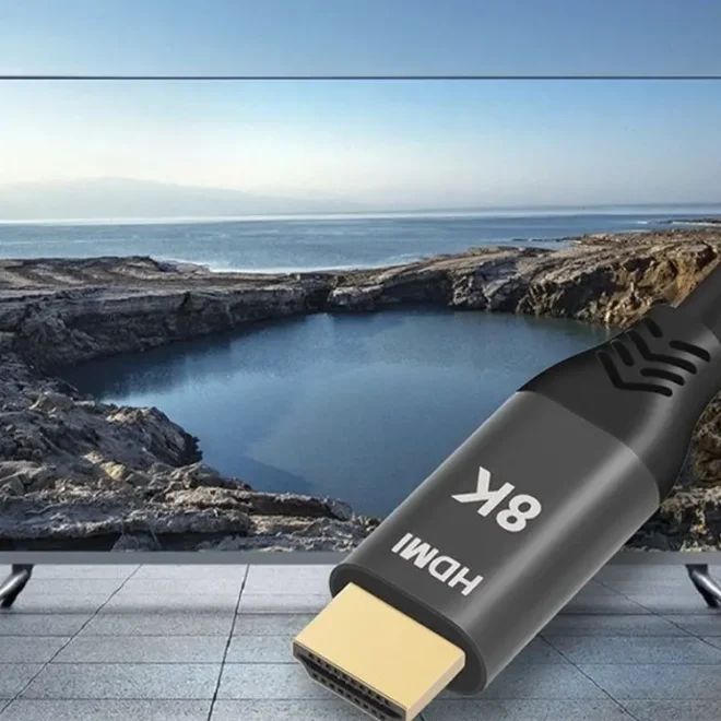 HDMI kabel podporující skutečné 8K rozlišení připojený k televizoru, který zobrazuje krajinu s jezerem a horami na obzoru.