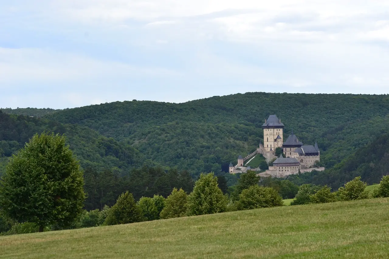 Hrad Karlštejn v pohádkové krajině, obklopený rozlehlými kopci, které mu dodávají jedinečný středověký nádech.