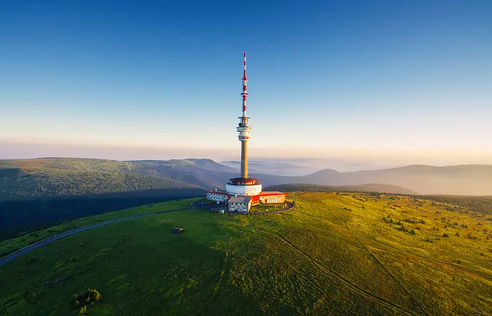 Pohled na vrchol Pradědu v Jeseníkách, s vysílačem a panoramatickým výhledem na okolní hory.