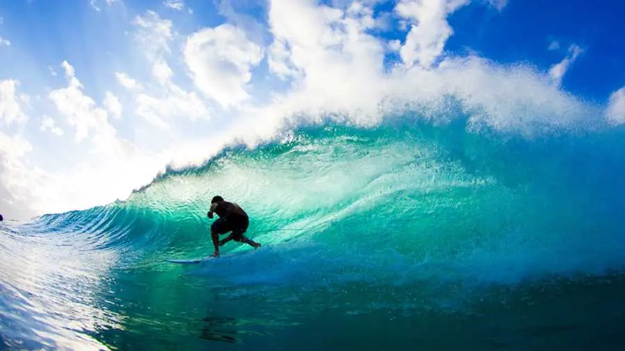 Surfař projíždí pod mohutnou vlnou při surfování na pláži Punta Mita, Mexiko, v jasný a slunečný den.