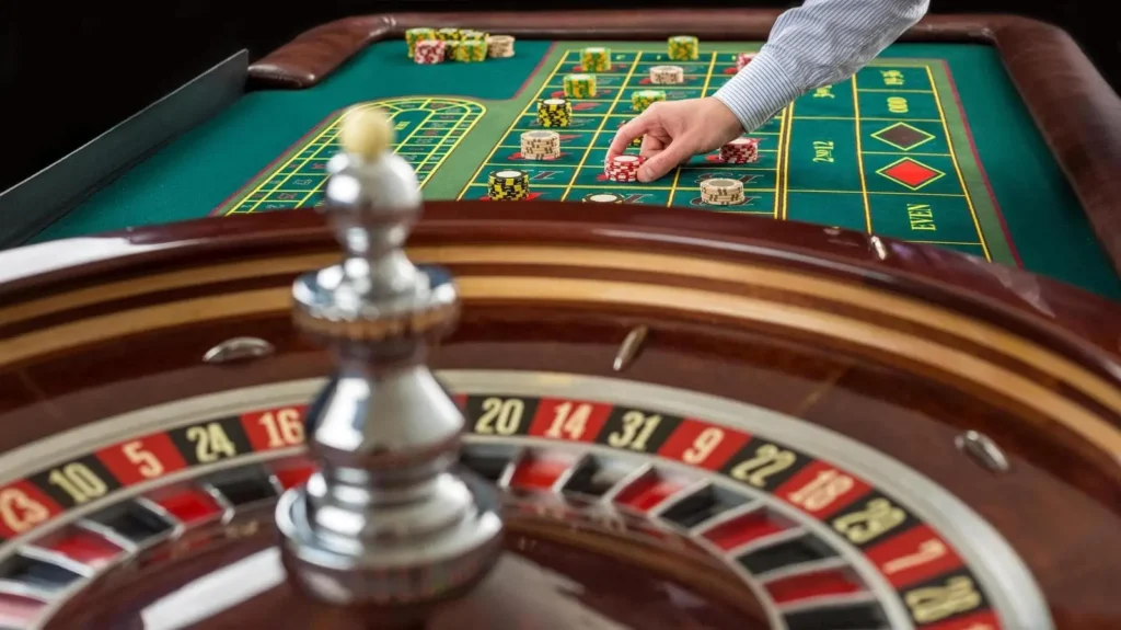 Ruleta v kasinu s roztočeným ruletovým kolem a hráčem pokládajícím žetony na herní stůl