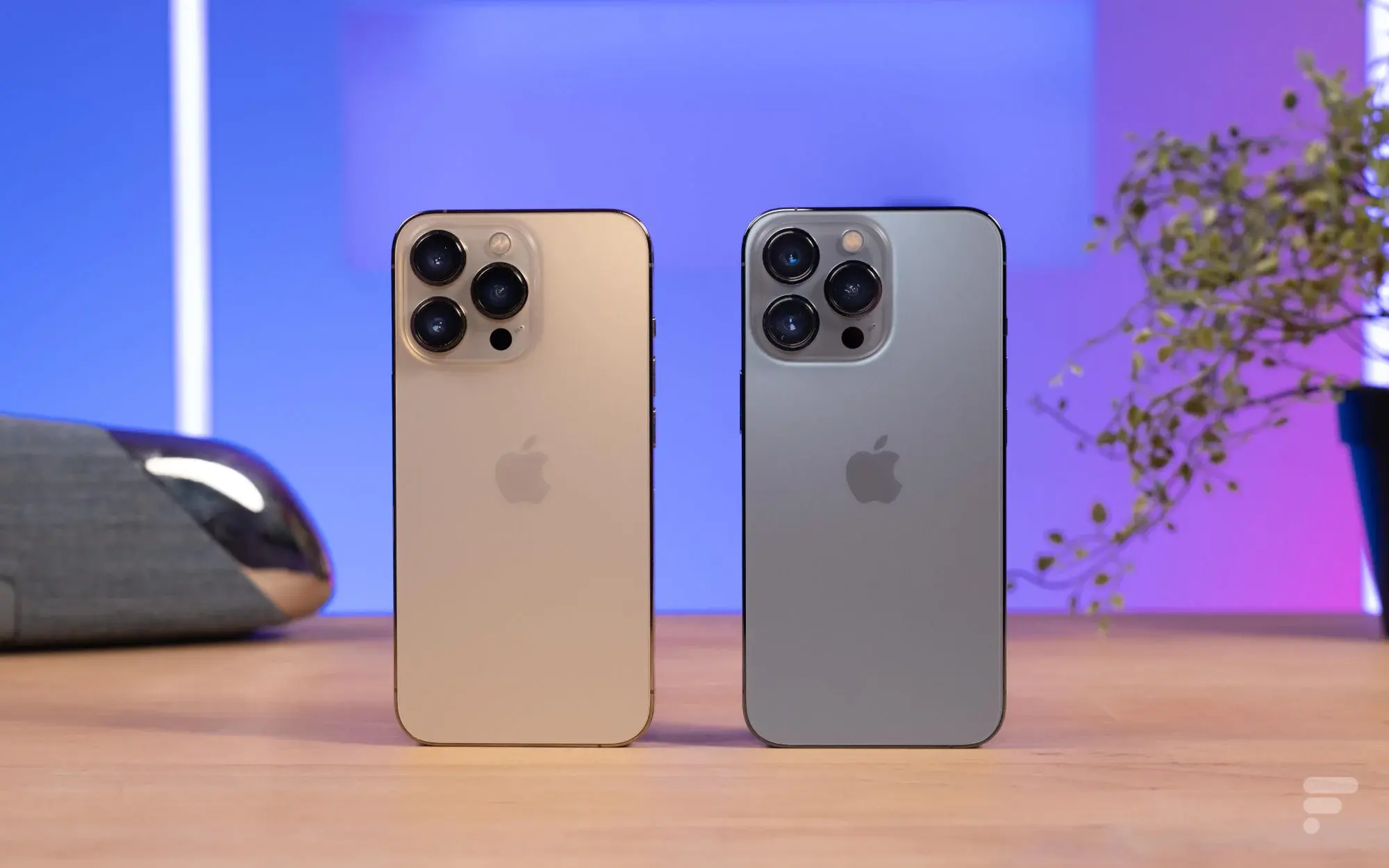 Zlatý a šedý model iPhone 13 Pro vedle sebe, ukazující jejich trojité zadní fotoaparáty. Tyto prémiové modely jsou známé svou vylepšenou fotografickou technologií a výkonem s čipem A15 Bionic.