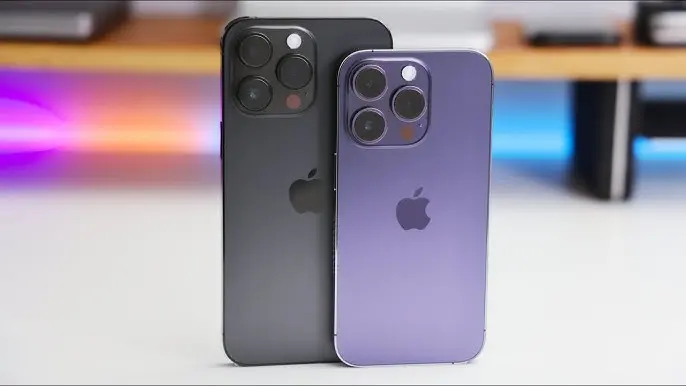 Fialový a černý model iPhone 14 Pro a 14 Pro Max vedle sebe, vyznačující se trojitým zadním fotoaparátem a elegantním titanovým rámem. Tyto modely přinesly inovace jako Dynamic Island a vylepšené možnosti natáčení videí.