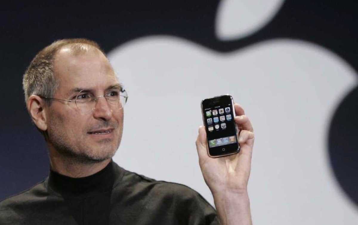 Steve Jobs drží v ruce první iPhone 2G při jeho oficiálním představení v roce 2007. Tento historický moment změnil svět mobilní komunikace, když byl představen revoluční dotykový telefon s jednoduchým designem a inovativním operačním systémem iOS.