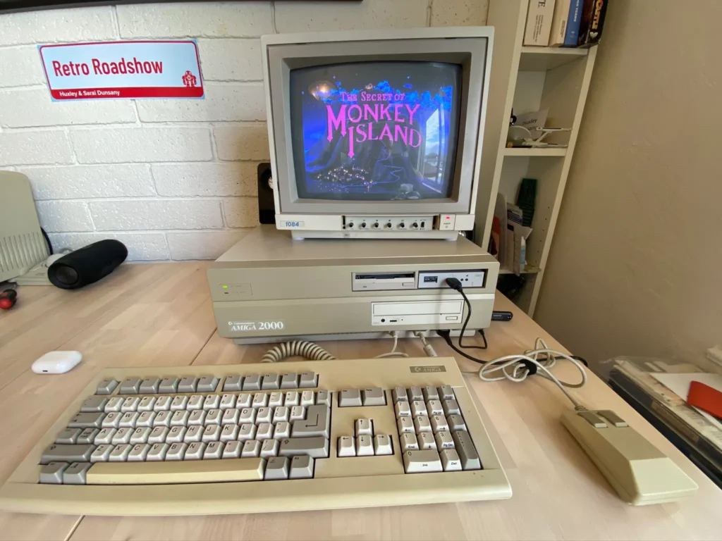 Profesionální model Amiga 2000 se širokým monitorem a otevřenou hrou "The Secret of Monkey Island" na obrazovce. Tento model byl často používán v komerčních aplikacích a díky svému výkonu se stal standardem ve video produkci a grafice.