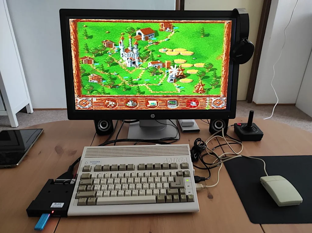 Nastavený herní systém Amiga 600 s moderním monitorem, ukazující ikonickou hru z 90. let. Amiga 600 je kompaktnější verze svého předchůdce a byla oblíbená mezi hráči a nadšenci do retro her.