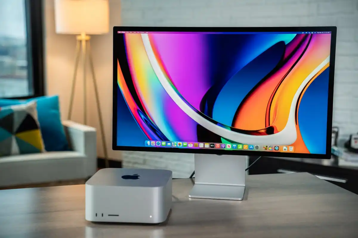 Apple Mac Studio připojený k jednomu Studio Display monitoru s barevným zobrazením, umístěný v moderním interiéru s pohodlným prostředím.