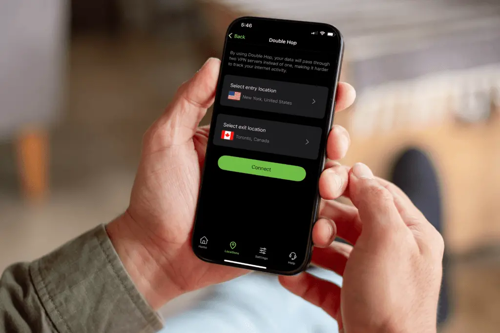 Pohled na mobilní telefon, kde je na obrazovce aplikace VPN s funkcí Double Hop. Uživatelské rozhraní ukazuje výběr vstupní a výstupní lokace, například New York a Toronto, a tlačítko „Connect“.