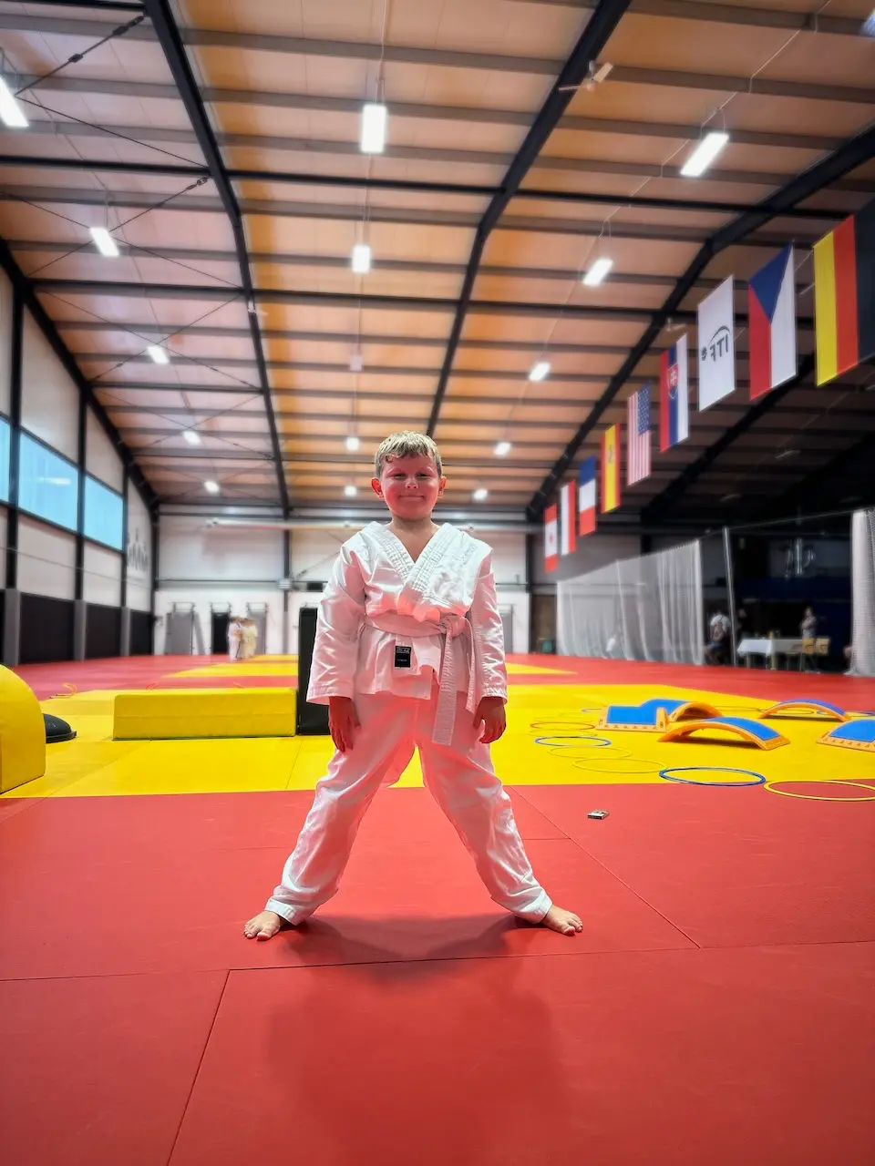 Šestiletý Matyáš v bílém kimonu stojí připraven na tatami v hale Krpálek Academy.