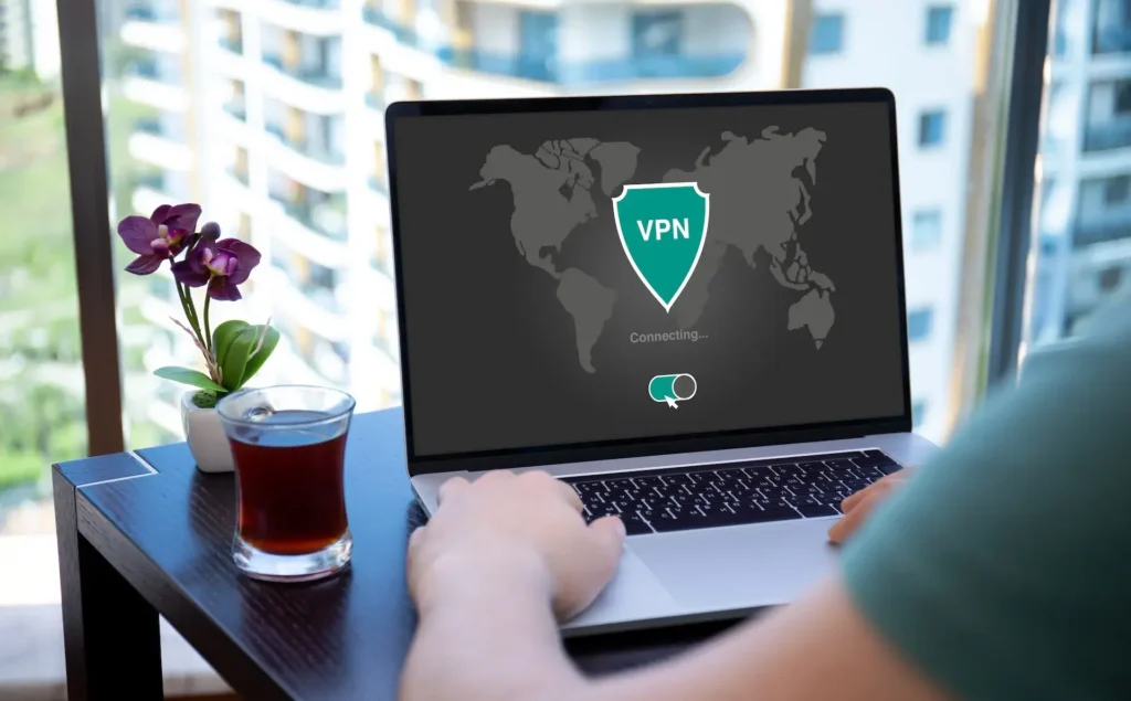 Osoba používající notebook s aktivní VPN připojením, zobrazující mapu světa na obrazovce; ideální řešení pro bezpečné a anonymní surfování na internetu.