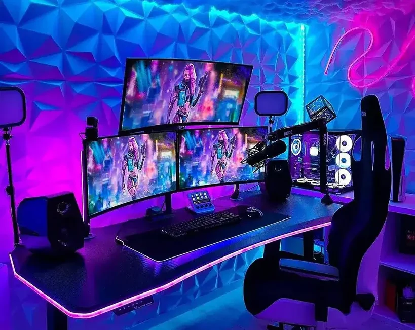 Herní setup s moderním a futuristickým designem, který zahrnuje trojitý monitor s neonovým podsvícením, herní klávesnici a mikrofon. Stůl má elegantní černý povrch s LED osvětlením po okrajích a židle s ergonomickým designem poskytuje maximální pohodlí. Na stěnách je 3D geometrický vzor v kombinaci modrých a fialových odstínů a strop je ozdoben imitací oblak s jemným podsvícením, které vytváří atmosférické osvětlení ideální pro hraní her.