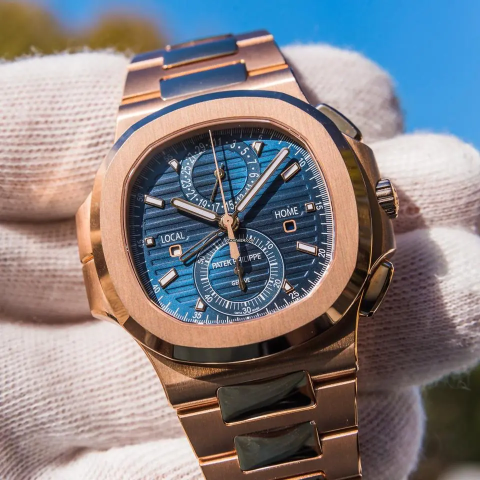 Hodinky Patek Philippe Nautilus se zlatým pouzdrem a modrým ciferníkem, držené v bílé rukavici.