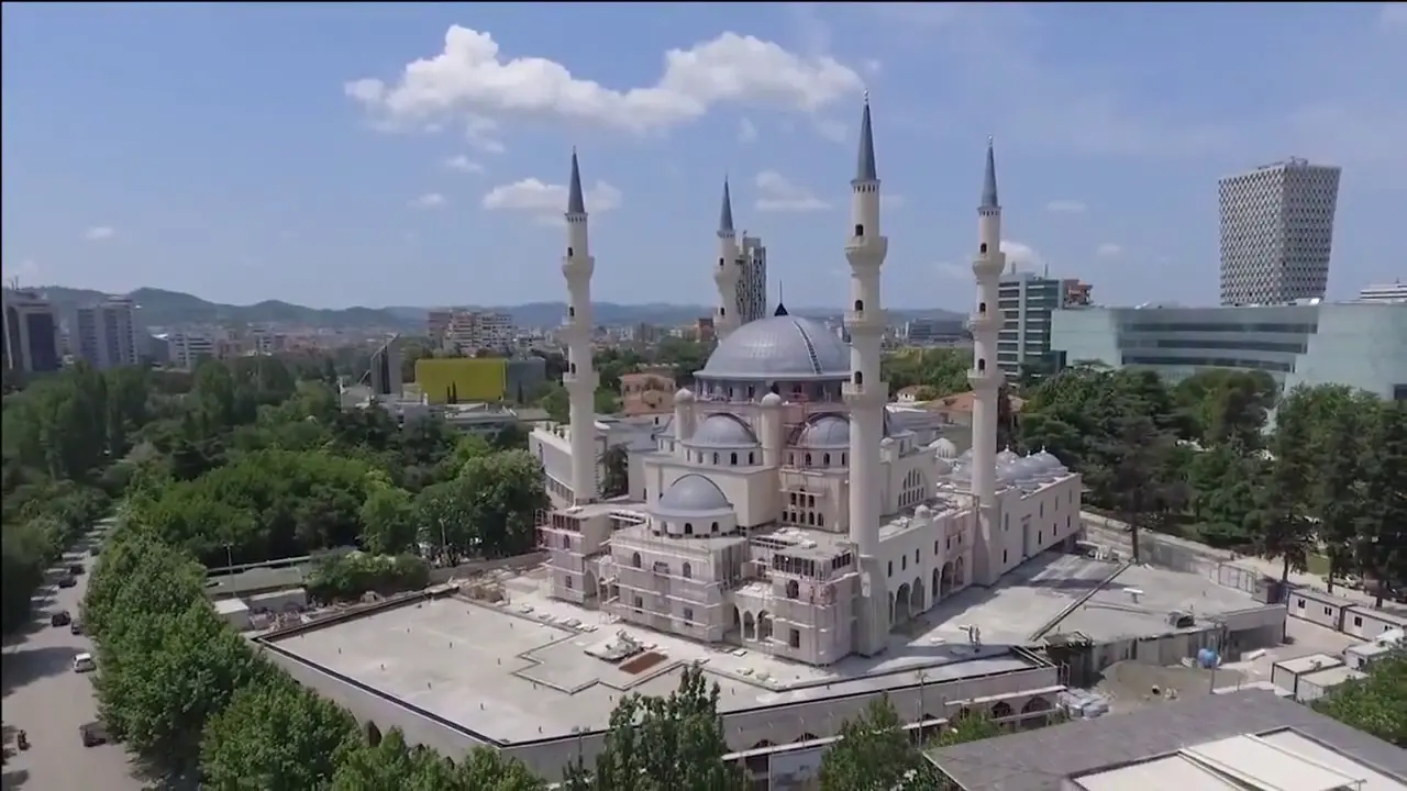 Letecký pohled na Velkou mešitu v Tiraně s jejími čtyřmi vysokými minarety a osmanskou architekturou, obklopenou zelení a městskou zástavbou.