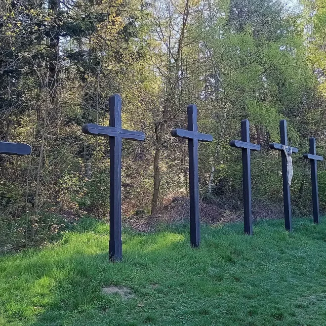 Devět černých křížů stojících v řadě u lesa na místě tragické události, která inspirovala legendu o Devíti křížích.